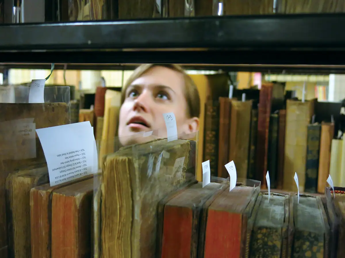 A person looking at old books in stacks