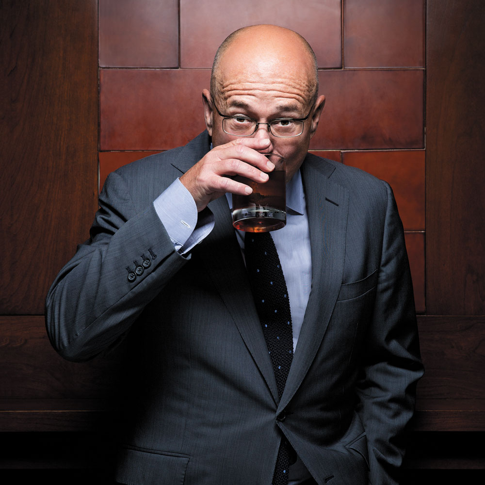 David Granger sipping a drink while wearing coat and tie