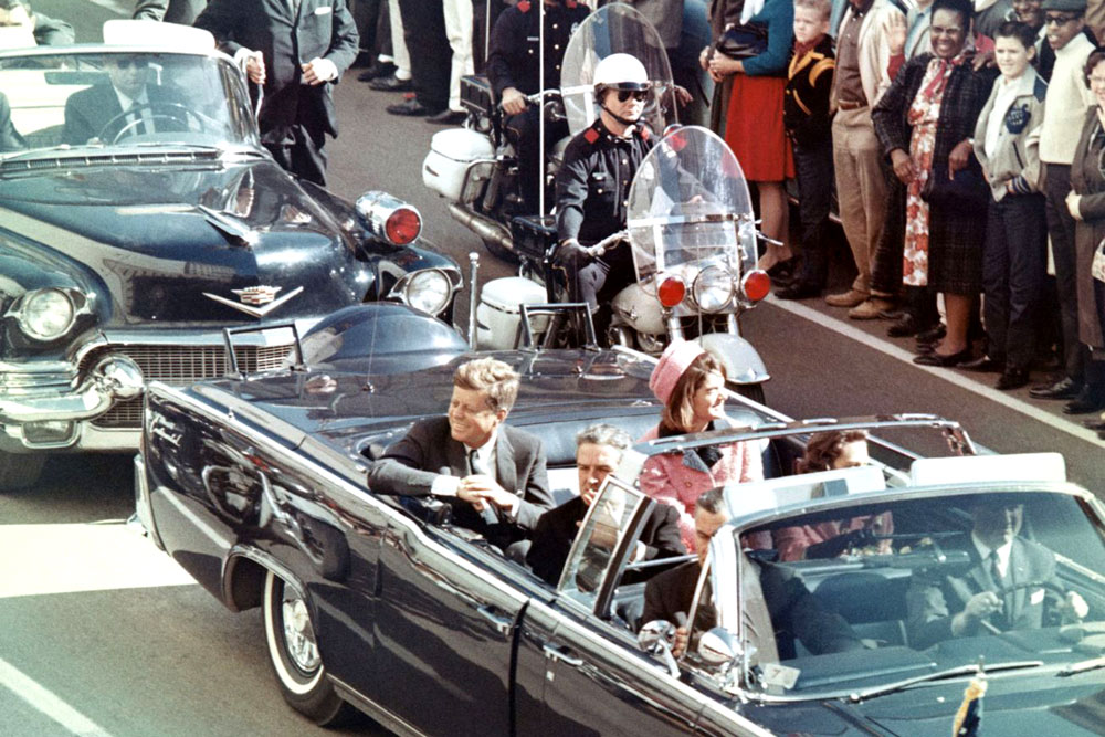 President John F. Kennedy riding in his limousine before being assassinated