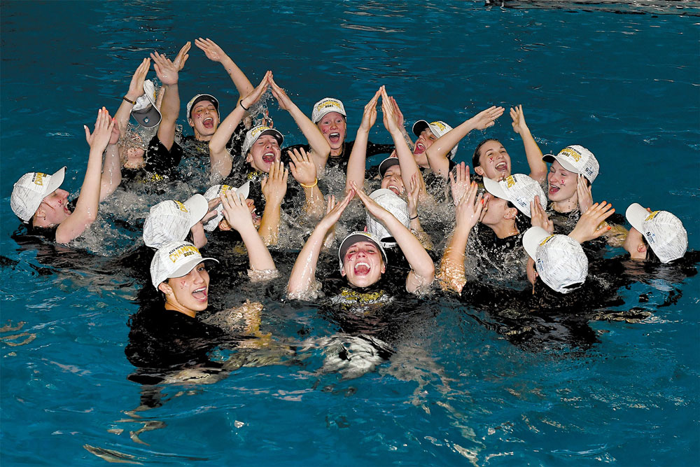 Members of the UVA’s women’s swimming and diving team celebrating in a pool